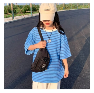 Vue extérieure d'un sac banane noir en tissu Oxford porté avec un t-shirt rayé bleu