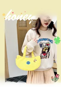 Detail view of yellow canvas handbag with KeepKind logo and cute embroidered smiley face
