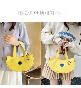 Detail of yellow crescent canvas tote with smile pattern and KeepKind embroidery logo