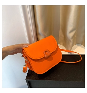Detail of bright orange saddle bag with glossy PU finish and square buckle decor