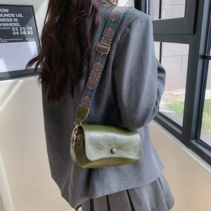 Dark green leather saddle bag with colorful embroidered wide strap shown on model