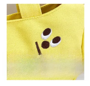 Close-up of vibrant yellow canvas tote bag showing fine texture and smile embroidery