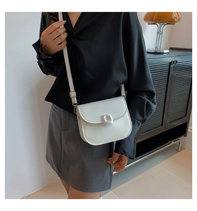 Detailed view of a white leather saddle bag with a minimalist square buckle detail