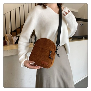Detail view of brown corduroy shell bag with adjustable strap in a cafe setting