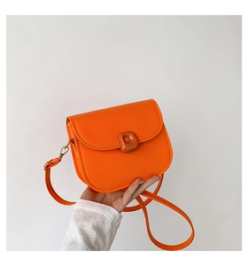 Detailed close-up of orange faux leather saddle bag with matte finish and matching buckle