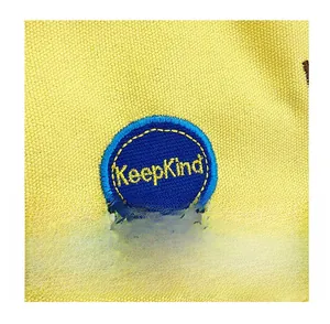Close-up of KeepKind embroidery on yellow canvas bag showing texture and stitching details