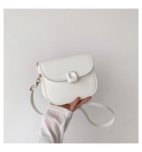 Detailed view of a white minimalist saddle bag with unique pebble-shaped buckle and gold hardware