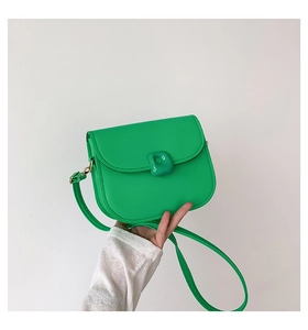 Detail of lime green leather saddle bag featuring a stylish square decorative buckle