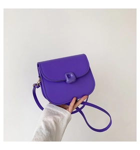 Detail of a bright purple crossbody saddle bag with a unique matching translucent buckle
