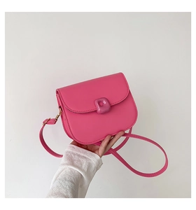Detailed view of pink leather saddle bag with square buckle and adjustable strap