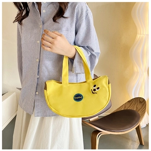 Detail of a yellow canvas handbag with a black smile embroidery and KeepKind woven label