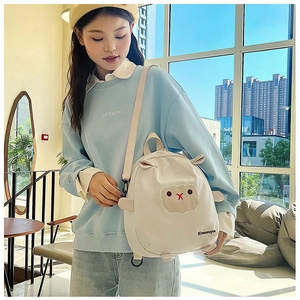 Vue détaillée d'un sac à dos enfant blanc en forme de mouton avec broderie et sangles