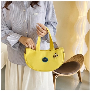 Close-up of bright yellow canvas crescent handbag featuring cute embroidered smiley face