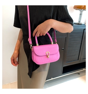 Dettaglio borsa rosa acceso con texture coccodrillo, fibbia dorata e tracolla regolabile
