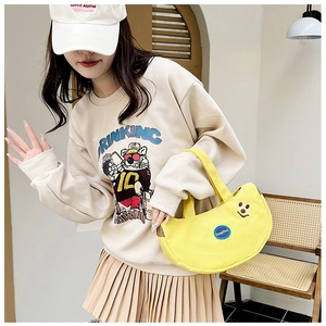 Detail of a bright yellow crescent canvas handbag paired with a cute embroidered sweatshirt