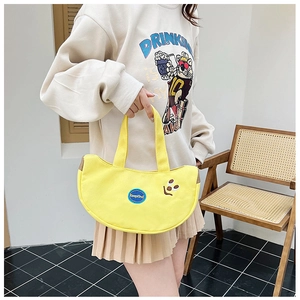 Detail of yellow canvas handbag featuring KeepKind embroidery and leather trim