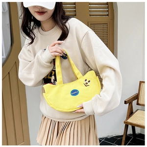 Detail of yellow canvas handbag featuring smile embroidery and KeepKind blue patch label