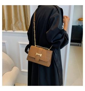 Detail view of brown crocodile texture leather bag with gold H clasp and chain strap