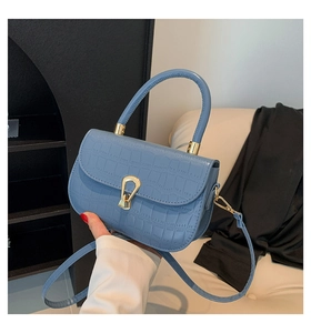 Dettaglio della borsa blu con motivo a coccodrillo, fibbia dorata e tracolla in pelle