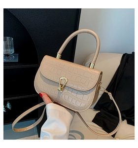 Dettaglio della borsa beige con motivo a coccodrillo, fibbia dorata e trama in pelle