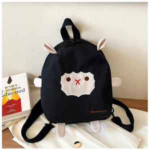 Détail du sac à dos mouton noir avec membres 3D blancs et visage brodé sur textile noir