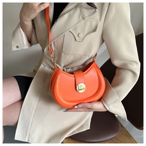 Detail of a bright orange half-moon crossbody bag with gold metal buckle and leather strap