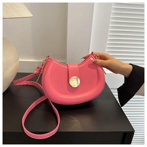 Close-up of pink crescent moon shoulder bag with golden round buckle and smooth PU leather