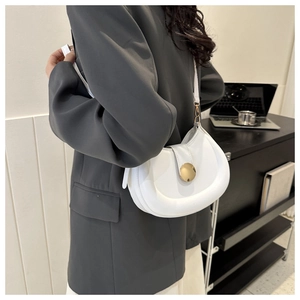 Macro shot of white leather crescent bag with golden metal clasp in office setting