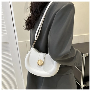 Chic white crescent shoulder bag with gold metal buckle shown on model in home setting