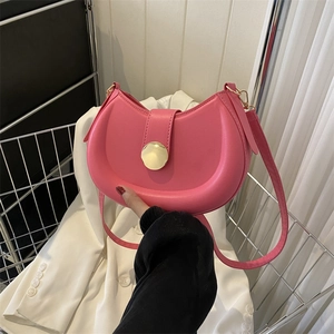 Detail of pink half-moon shoulder bag with golden round buckle and smooth leather texture