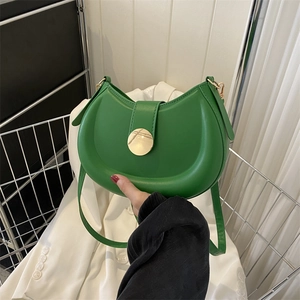 Detail of green crescent shoulder bag featuring smooth leather and gold round metal buckle