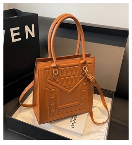 Detail of caramel brown tote bag with geometric triangle embossing and gold hardware