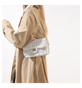 Gros plan d'un sac bandoulière en tweed crème avec chaîne dorée porté par un mannequin