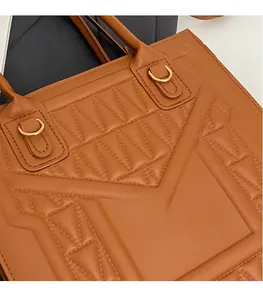 Detailed close-up of caramel brown tote bag featuring geometric quilted texture and gold hardware