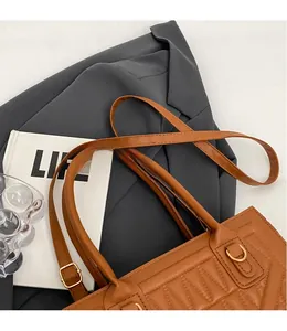 Detail of caramel brown PU leather bag with V-shaped quilting and golden metal hardware