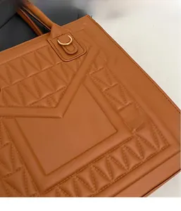Detail of brown faux leather tote with geometric triangle quilting and gold hardware
