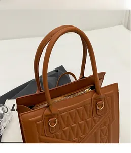 Close-up of brown quilted faux leather tote bag with sturdy handles and golden metal rings