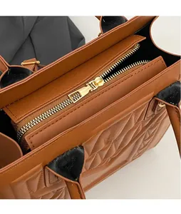 Close-up of polished gold-toned metal zipper on a brown quilted faux leather handbag