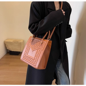 Close-up of brown textured crossbody bag with geometric V-pattern engraving for women