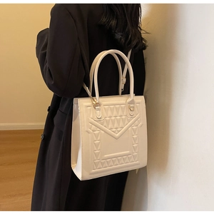 Close-up of a white textured crossbody bag featuring modern geometric quilted patterns