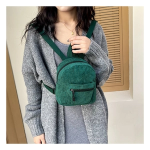Detail of green corduroy backpack showing soft ribbed texture and zippered pocket