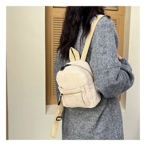 Detail of beige corduroy mini backpack with yellow nylon straps on a model back