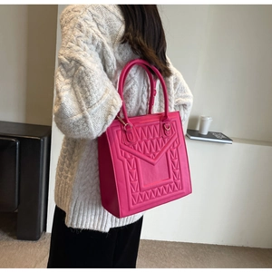 Macro detail of magenta structured handbag featuring geometric embossed patterns and gold hardware