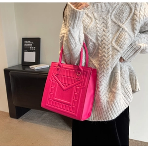 Detailed view of rose red tote bag featuring geometric 3D embossed pattern and top handles