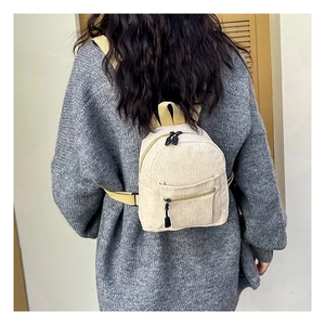 Detailed view of beige corduroy backpack texture and straps on a person's back