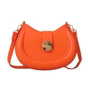Orange leather crescent shoulder bag with large gold metal buckle on a white background