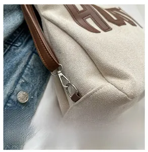 Detailed close-up of the silver metal hook and brown leather handle on a canvas tote bag