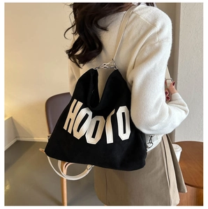 Detail of the adjustable white strap and silver buckle on a black HOOTO canvas tote bag