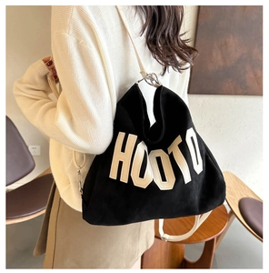 Detail of black canvas tote bag showing white HOOTO letter patch and metal hook