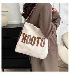 Detail of canvas tote bag with HOOTO letter patch and brown shoulder strap